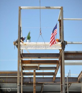Workers secure the final structural beam to the facility during the “Topping Off” celebration Friday (April 12).