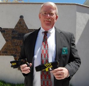 Captain Don Ford shows the size difference between the new and the old Tasers.
